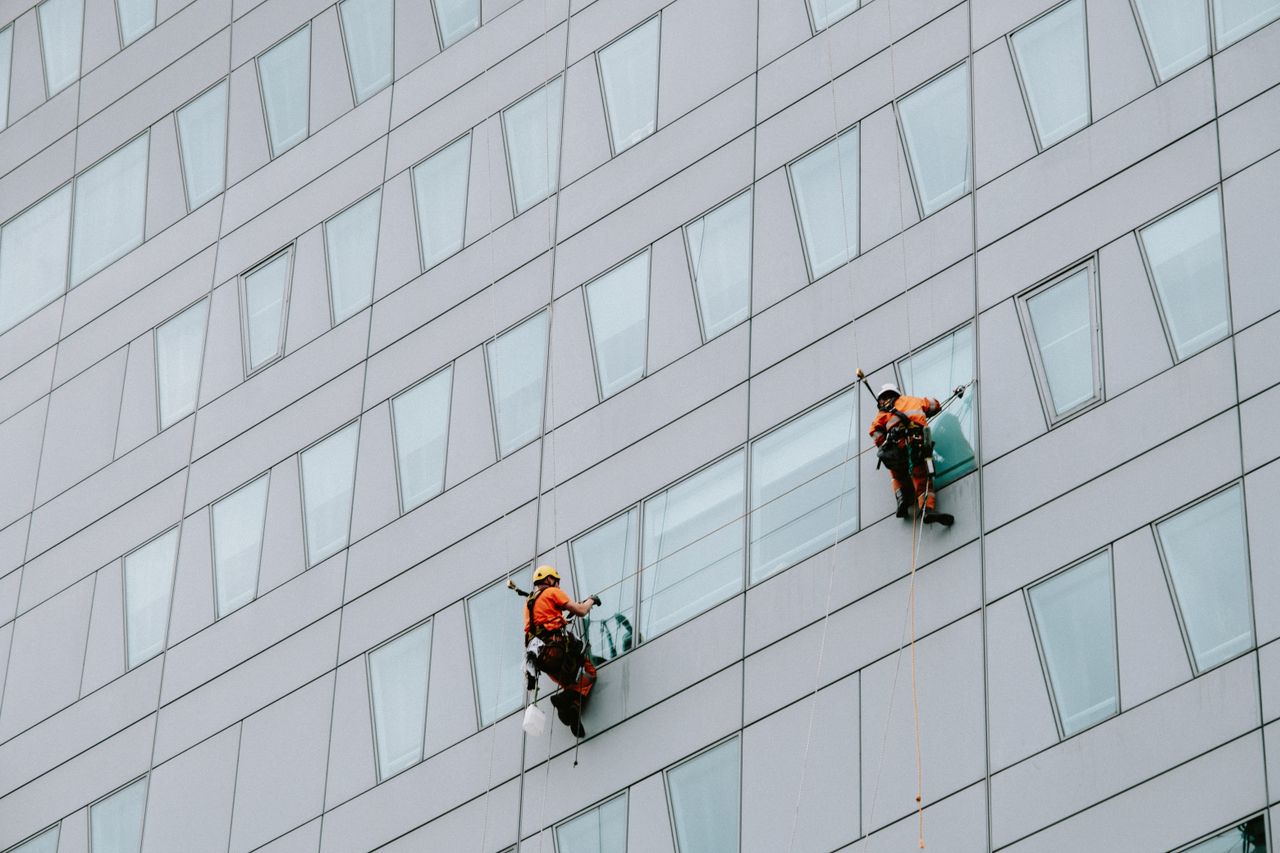 about-01 High-rise window washers in safety gear cleaning a skyscraper facade.